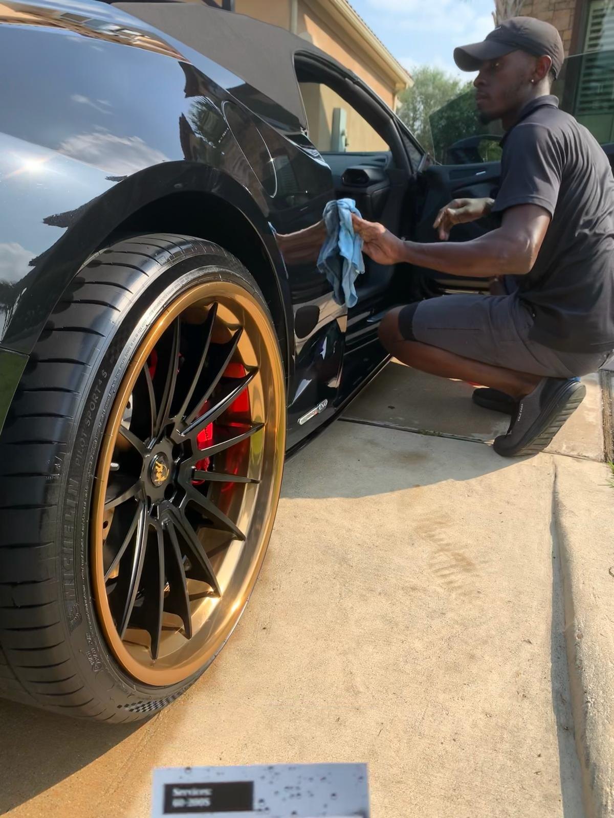 Platinums technician hand-drying a black Porsche in a Katy, Texas driveway